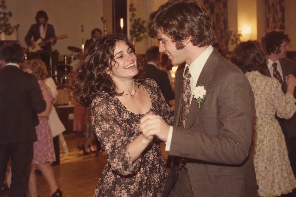 Illustrative 1970s colour photograph of a young couple laughing as they dance in a village hall
